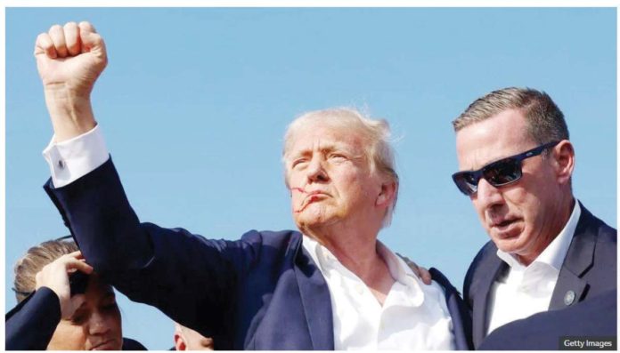 Donald Trump raises a fist as he is taken to safety following an attempt on his life during a campaign rally. GETTY IMAGES