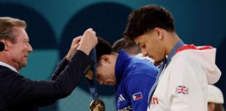 Olympic gymnastics gold medalist Carlos Edriel Yulo receives his medal as Jake Jarman of Britain looks at his bronze medal. RAPPLER PHOTO