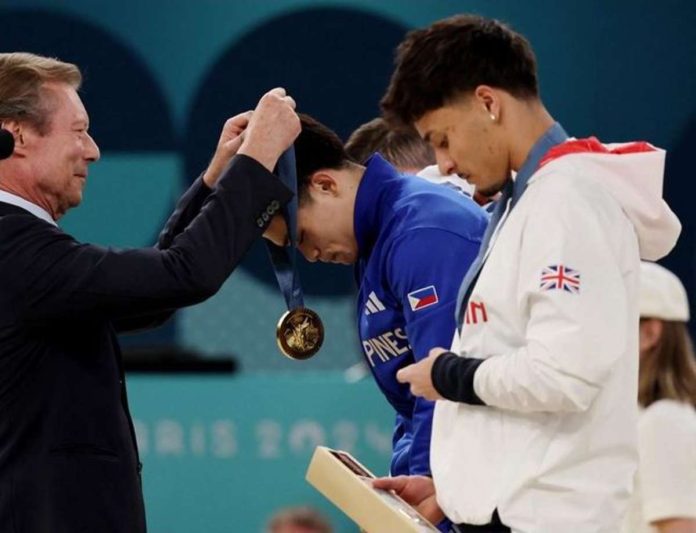 Olympic gymnastics gold medalist Carlos Edriel Yulo receives his medal as Jake Jarman of Britain looks at his bronze medal. RAPPLER PHOTO