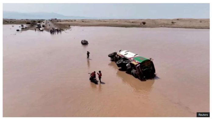Yemen_resized People stand next to an overturned vehicle in flood waters in Yemen. REUTERS