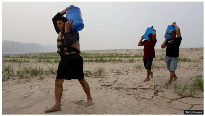 Brazil_resized People carry drinking water along a sandbank of Madeira River in Paraizinho Community, in Humaita, Amazonas state, northern Brazil. Rivers are dying up. GETTY IMAGES