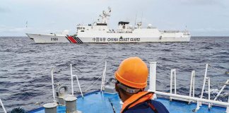 A crew member of BRP Cabra observes a China Coast Guard vessel monitoring, in turn, the Philippine Coast Guard ship. —AFP. 