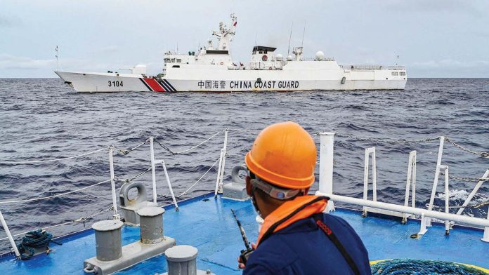 Chinese_1_resized A crew member of BRP Cabra observes a China Coast Guard vessel monitoring, in turn, the Philippine Coast Guard ship. —AFP.