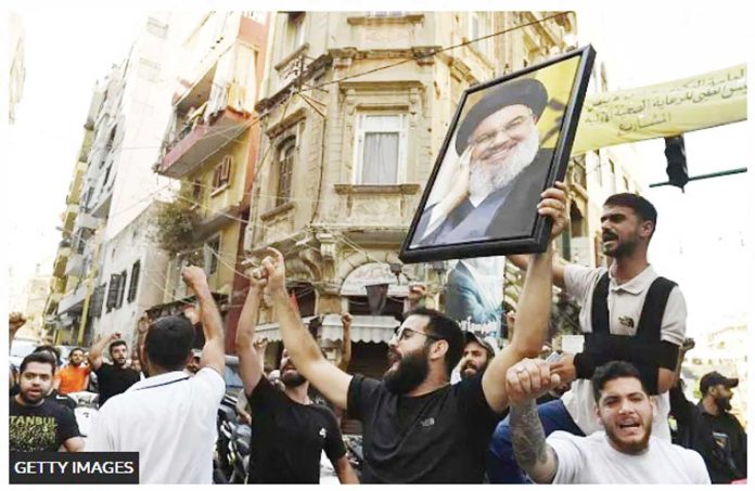 A group in Beirut, Lebanon carry a photo of slain Hezbollah leader Hassan Nasrallah and chant slogans. GETTY IMAGES