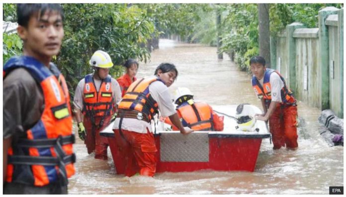 Rescue volunteers with a boat wade through a flooded road in Taungoo, Myanmar, on September 12, 2024, amid heavy rains triggered by Typhoon Yagi. EPA