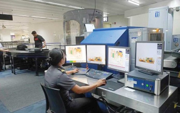 NAIA-workers-1 Manila International Airport Authority personnel are assured to still have their jobs once the government turns over the operations and maintenance of the Ninoy Aquino International Airport (NAIA) to the private concessionaire. Photo shows a baggage screener at the NAIA Terminal 1. PHOTO COURTESY OF OFFICE FOR TRANSPORTATION SECURITY