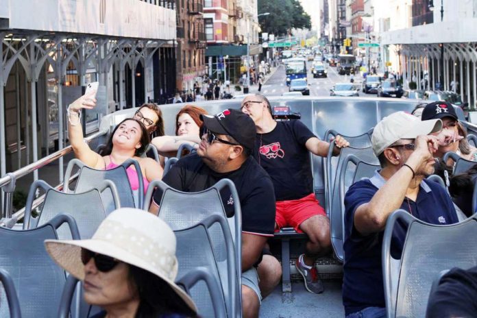 travel_industry_1_resized A tourist takes a group selfie on the ‘Big Bus’ at Times Square in New York City on August 27, 2024. REUTERS/KENT J EDWARDS PHOTO