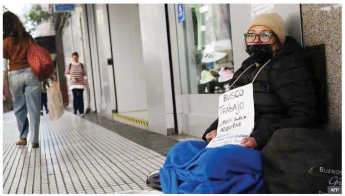 Argentina_1_resized An unemployed Argentinian woman sits on a street holding a sign that reads “I am looking for a job in order to be able to rent” in Buenos Aires. AFP