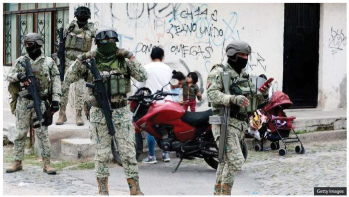 Mexico_1_resized Four Mexican army soldiers stand guard. They are armed with assault rifles, as well as wearing full military gear and facemask. GETTY IMAGES