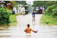 Honduran villages cut off by torrential rain A shirtless man wearing a brown hat and holding his flip flops in one hand wades across waist-deep water while people watch from the other side of an inundated road in El Progreso, Honduras. Many roads and bridges became impassable after days of rain. REUTERS