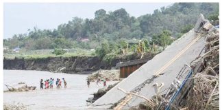 People cross a river next to a bridge that collapsed after the river overflew due to heavy rains brought about by Severe Tropical Storm Kristine in Laurel, Batangas province, south of Manila on October 25, 2024. Photo by Ted ALJIBE / AFP