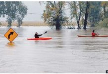 Storms threaten US holiday travels Kayakers row passed a street sign on a flooded road in California. GETTY IMAGES