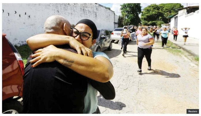 Venezuela_1_resized Two people are seen embracing tightly on a street in Tocuyito, Venezuela, with a group of people walking in the background and cars parked along the road. Venezuela released over 100 people arrested following July’s contested presidential election. REUTERS