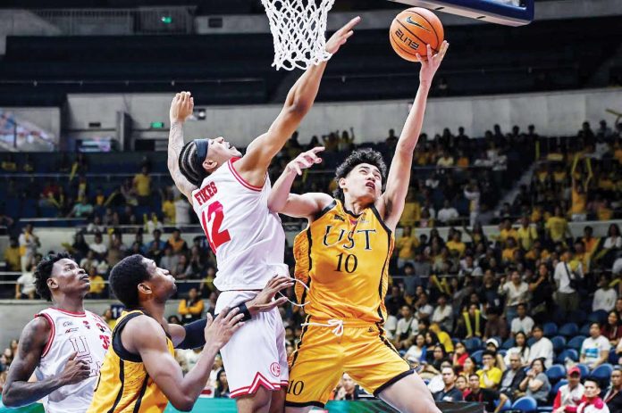 sports-UST-1 University of Santo Tomas Growling Tigers’ Angelo Crisostomo goes for a tough basket against the defense of University of the East Red Warriors’ Devin Fikes. UAAP PHOTO