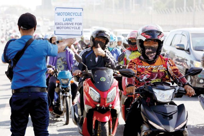 COA_LTO_1_resized A motorcycle rider flashes the thumbs-up sign to a traffic constable carrying a placard that reads “Motorcycle Lane Exclusive for Motorcycle” along Commonwealth Avenue in Quezon City. PNA
