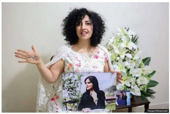 Iran_resized Narges Mohammadi Narges Mohammadi, wearing a white dress with flower patterns on it, holds out her right hand to show a message written on it, while holding a photo in her left hand. The photo is Mahsa Amini, whose death in custody triggered protests in Iran. Narges Mohammadi Photo