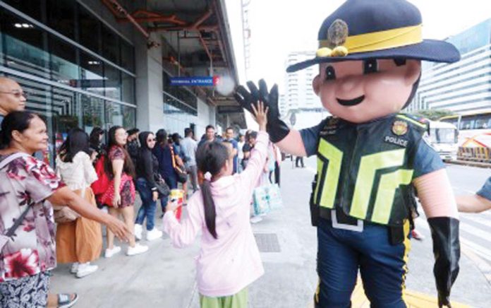 PUV-permits-1 A mascot of the Philippine National Police greets a child with a high five outside the Parañaque Integrated Terminal Exchange on Oct. 31, 2024. The Land Transportation Franchising and Regulatory Board on Thursday, Dec. 19, 2024, said it issued 956 special permits to public utility vehicles (PUV), increasing the number of available PUVs such as buses in routes that will be particularly busy during the holiday season. PNA PHOTO BY AVITO DALAN