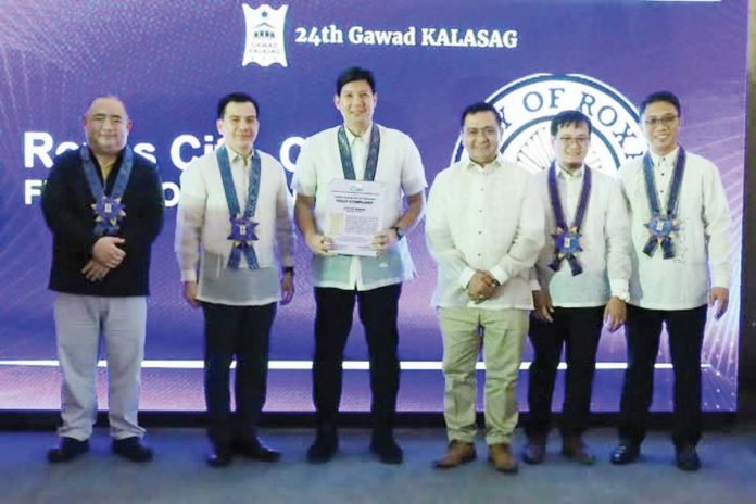 roxas_kalasag_1_resized Mayor Ronnie Dadivas (third from left) and City Disaster Risk Reduction and Management head Pong Saneo (fourth from left) receive the “Beyond Compliant” seal of the Gawad Kalasag for Roxas City during the awarding ceremony in Iloilo City on Dec. 11, 2024. MAYOR RONNIE DADIVAS FACEBOOK PAGE PHOTO