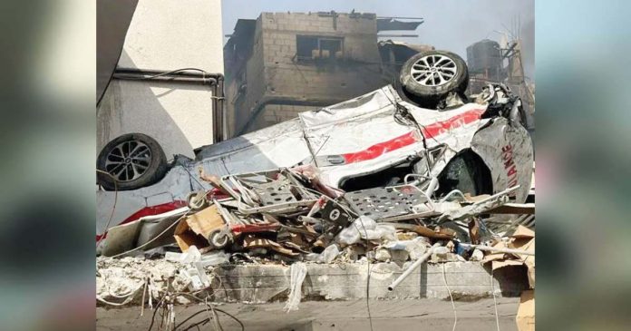 Israel-1_superimposed A damaged ambulance is seen upside down outside Kamal Adwan hospital in Beit Lahia, northern Gaza Strip. AFP