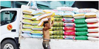 A worker unloads a sack of imported rice from a truck in Tondo, Manila. The public can expect a reduction in the retail prices of rice and pork in the coming days, according to the Presidential Communications Office. PNA