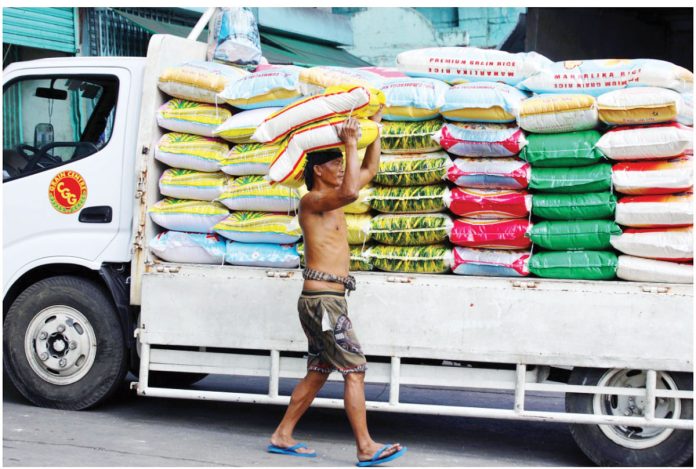 Price-1 A worker unloads a sack of imported rice from a truck in Tondo, Manila. The public can expect a reduction in the retail prices of rice and pork in the coming days, according to the Presidential Communications Office. PNA