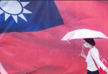 Taiwan revokes visa of pro-Beijing Chinese influencer A woman carrying an umbrella walks past a giant Taiwan flag. GETTY IMAGES
