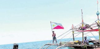 A fisherman waves the Philippine flag near a “payao,” or artificial reef close to Panatag (Scarborough) Shoal in the West Philippines Sea to display resistance to Chinese incursions and to show other foreign vessels passing through the area that these waters are part of the country’s exclusive economic zone. PHOTO FROM BIGKIS