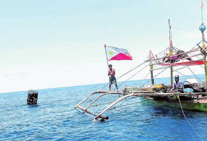 China_1_resized A fisherman waves the Philippine flag near a “payao,” or artificial reef close to Panatag (Scarborough) Shoal in the West Philippines Sea to display resistance to Chinese incursions and to show other foreign vessels passing through the area that these waters are part of the country’s exclusive economic zone. PHOTO FROM BIGKIS