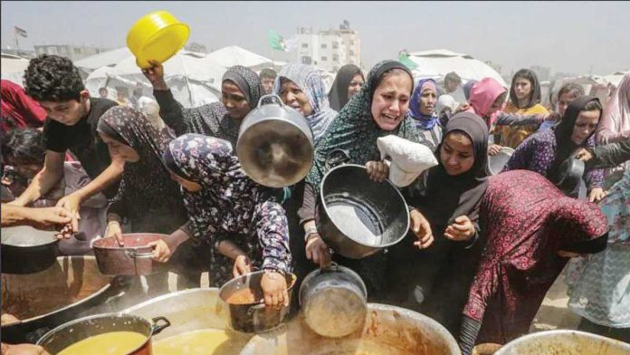 Displaced Palestinians gather to receive a portion of food from a charity kitchen, in Jabalia refugee camp, northern Gaza. EPA/SHUTTERSTOCK