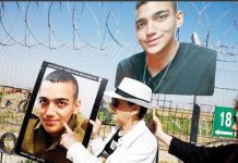 Varda Ben Baruch, grandmother of hostage Edan Alexander, wears a white hat and white jacket as she points at the portrait of Edan, next to the wire fence next to their kibbutz. REUTERS