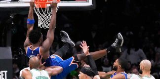 New York Knicks forward OG Anunoby hangs from the rim after dunking against the Boston Celtics' defense. AP PHOTO/CHARLES KRUPA