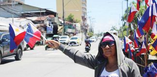 With flags in hand and resilience in her eyes, vendor Jane waves at passing vehicles along a busy Iloilo City street. Despite dwindling interest, she keeps the tradition alive — one flag, one hopeful gesture at a time.