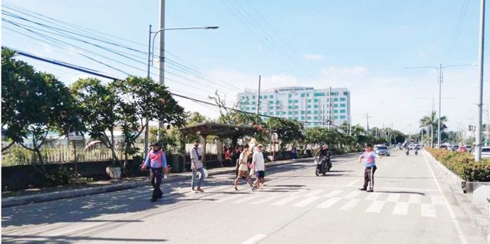Pedestrians cross a designated lane along the Sen. Benigno Aquino Sr. Avenue near in Barangay Ungka, Jaro, Iloilo City — one of several areas under scrutiny as the city reviews the safety, placement, and visibility of crosswalks following a fatal road incident involving a student. ICTTMO Photo