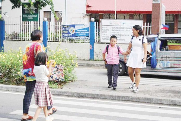 mai_opening_copy_resized Parents and guardians escort schoolchildren across a pedestrian lane near a public elementary school in Iloilo City during the first day of classes on June 16, 2025. Authorities reported a safe and orderly school opening across Western Visayas. AJ PALCULLO/PN