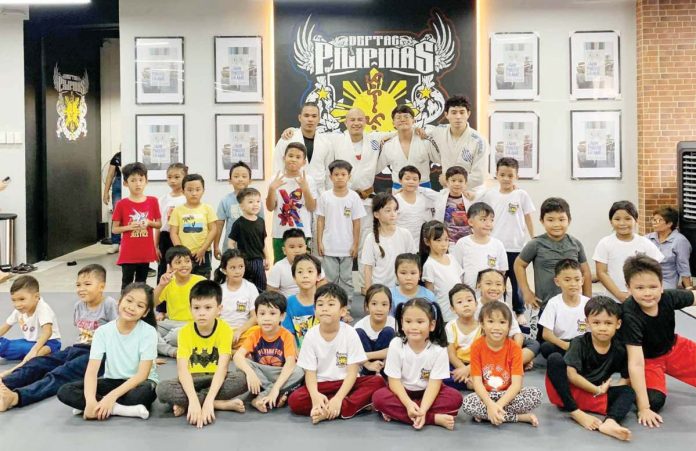 Young participants pose with jiujitsu instructors in this file photo. At a gym, they were introduced to basic grappling techniques and the values of discipline and self-defense. CONTRIBUTED PHOTO