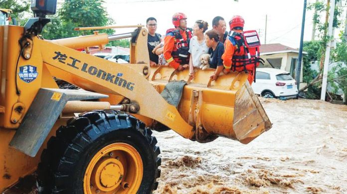 People are being lifted above floodwaters by a bulldozer in China. Floods in Beijing have submerged roads and left residents stranded. GETTY IMAGES
