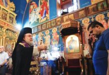 A priest stands in the Holy Family Church in Gaza as a mourner receives blessings during a funeral for those killed by an Israeli strike on the church. REUTERS