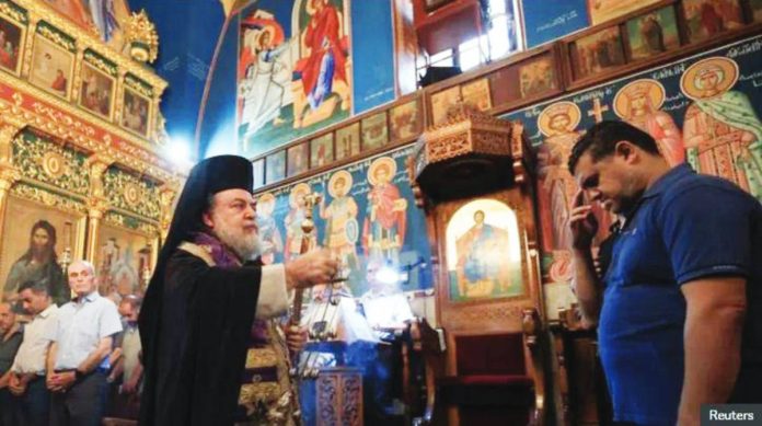 Israel copy A priest stands in the Holy Family Church in Gaza as a mourner receives blessings during a funeral for those killed by an Israeli strike on the church. REUTERS