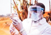 A medic in full protective face mask and white clothing holds up a vaccine syringe with gloved hands. A study has examined the impact of emergency vaccine roll-outs for five major infectious diseases, including Ebola. GETTY IMAGES