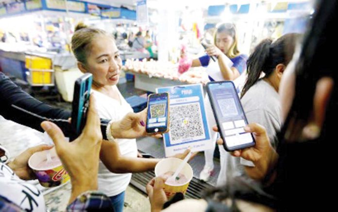 consumer-protection A seller shows a QR code to a customer to scan to pay for her purchase. Bangko Sentral ng Pilipinas Governor Eli Remolona Jr. on Thursday, July 3, 2025, cited how digitalization helps in monetary policy and consumer protection. PNA FILE PHOTO