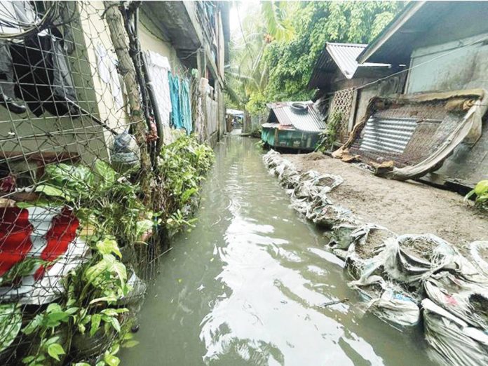 FLOODWATERS RISE IN TAGBAK. Knee-deep flooding inundates a residential alley in Barangay Tagbak, Jaro, Iloilo City on July 20, 2025, following days of heavy rain. Local officials and residents blame nearby Department of Public Works and Highways’ infrastructure projects for obstructing natural drainage paths, worsening the flood situation. PHOTO BY JENNY ROSE CAOYONAN PHOTO