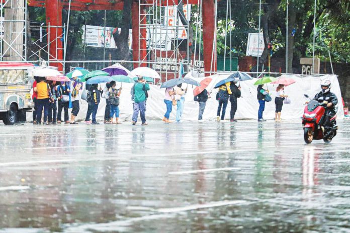The Department of Labor and Employment says employers in the private sector may suspend work to ensure the safety and health of their employees during weather disturbances. Photo shows commuters waiting for rides in Quezon City amid rains. PNA PHOTO BY ROBERT OSWALD P. ALFILER