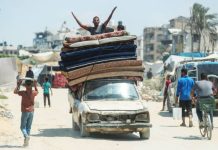 A displaced Palestinian man fleeing northern Gaza gestures atop a vehicle loaded with belongings while he heads south. Thousands of Palestinians have been fleeing from intensifying Israeli strikes in parts of Gaza City in recent days. REUTERS