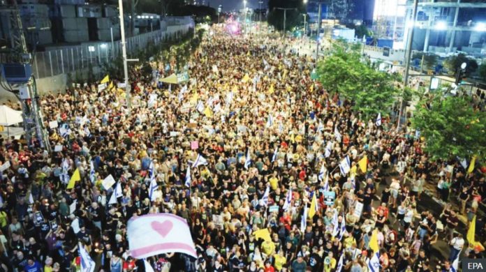 An aerial image shows a crowd of protesters filling a street, some waving yellow banners and displaying a white flag with a pink heart, calling for the release of Israeli hostages in Tel Aviv, Israel. EPA