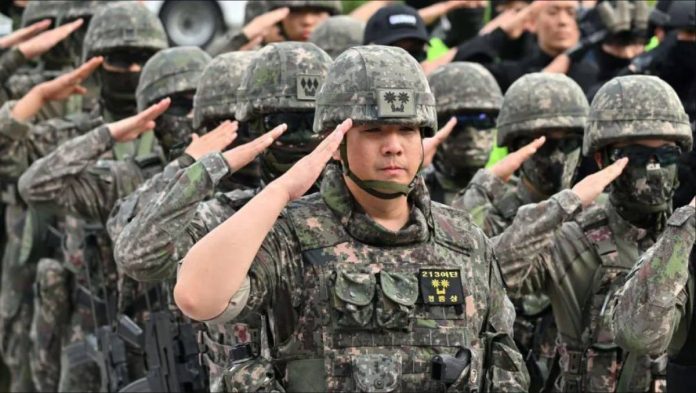 South Korean soldiers standing in neat rows, raising their hands in salute. The nation’s military has fallen below the 500,000 threshold that experts say is needed to maintain defense readiness. GETTY IMAGES