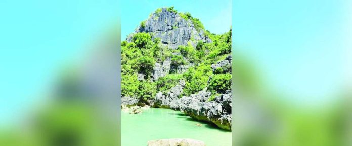 mai Tangke.JPG_superimposed The emerald waters of Tangke Saltwater Lagoon in Carles, Iloilo, are framed by towering limestone cliffs. The local government has ordered its temporary closure this September to ensure visitor safety during the southwest monsoon and allow the natural attraction to recover. MAI LADIAO/PN