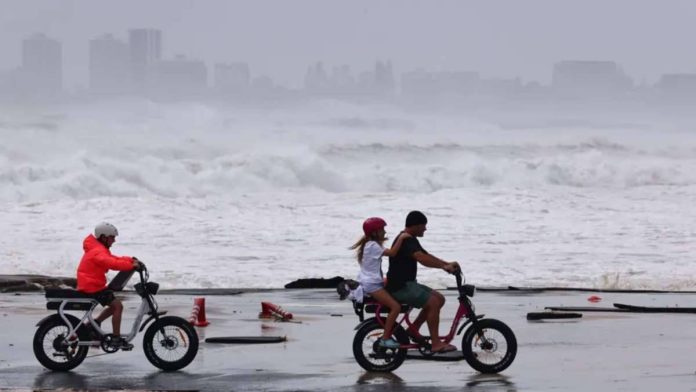 Australia_copy_resized Three people ride two bikes in the coast in Australia with waves crashing in the background. Australians are already living with the consequences of climate change. EPA