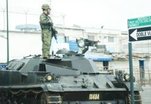 Two Ecuadorean soldiers stand guard atop a tank outside Machala prison, in Machala, Ecuador. AFP VIA GETTY IMAGES