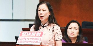 Hong Kong Lawmaker Maggie Chan makes a speech from a lectern adorned with a red and white sign that says in Chinese “resolutely oppose registration of same‑sex partnerships ordinance”. AFP