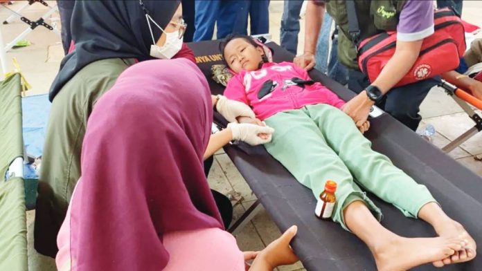 Indonesia A young girl lies on a foldout bed with a bottle of medicine resting against her leg. Thousands of school children have suffered food poisoning from a controversial free lunches programme in Indonesia. YULI SAPUTRA